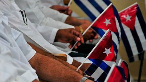 Manos de batas blancas con banderitas cubanas